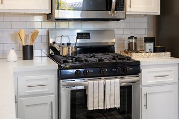 a kitchen with a stove and a microwave and white cabinets